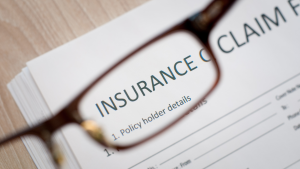 Close-up of an insurance claim form viewed through eyeglasses, symbolizing attention to detail and customer experience in insurance claims processing
